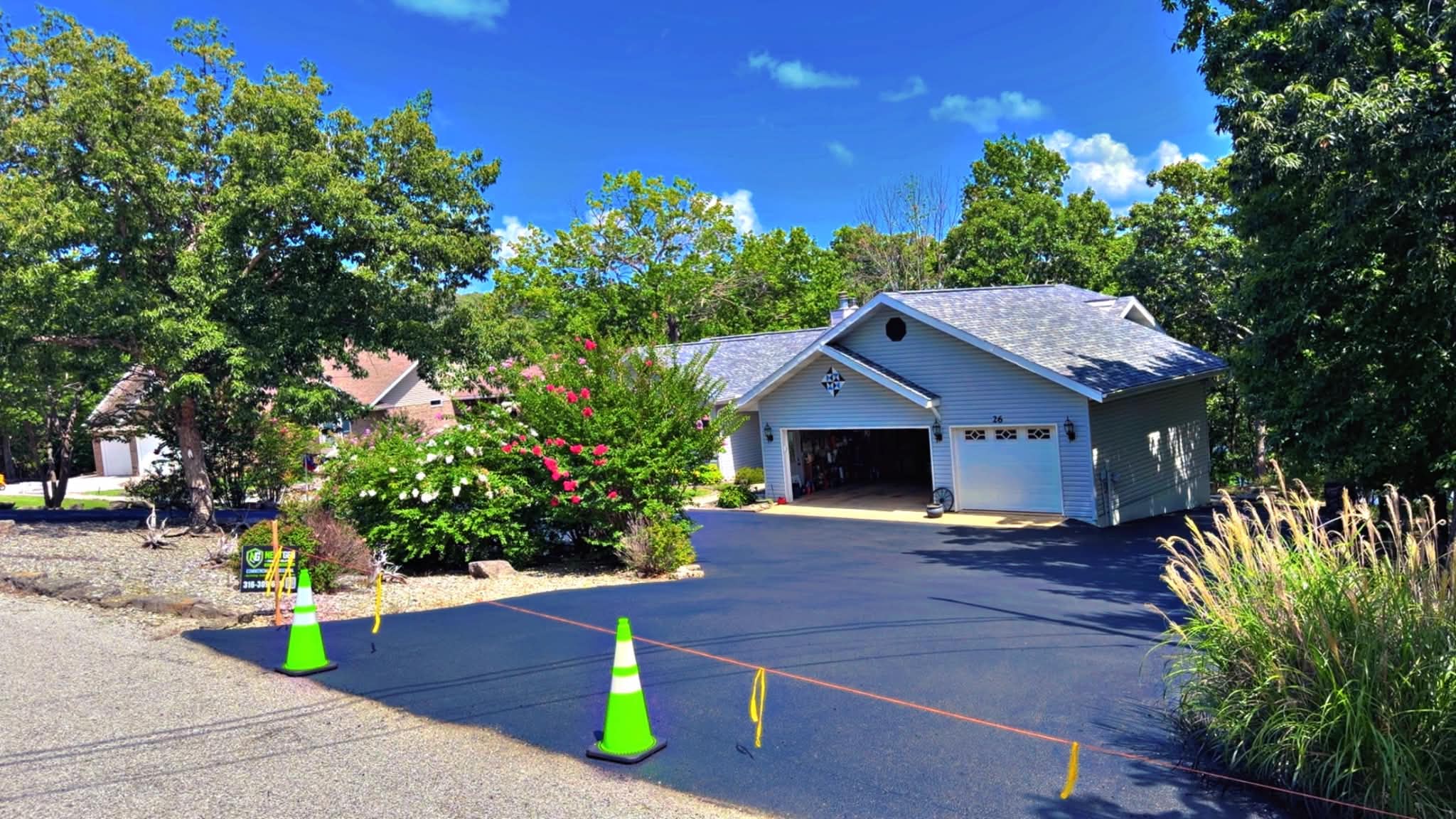 Professional Asphalt Maintenance Services in Wichita, KS Freshly sealcoated residential driveway with cones and protected landscaping