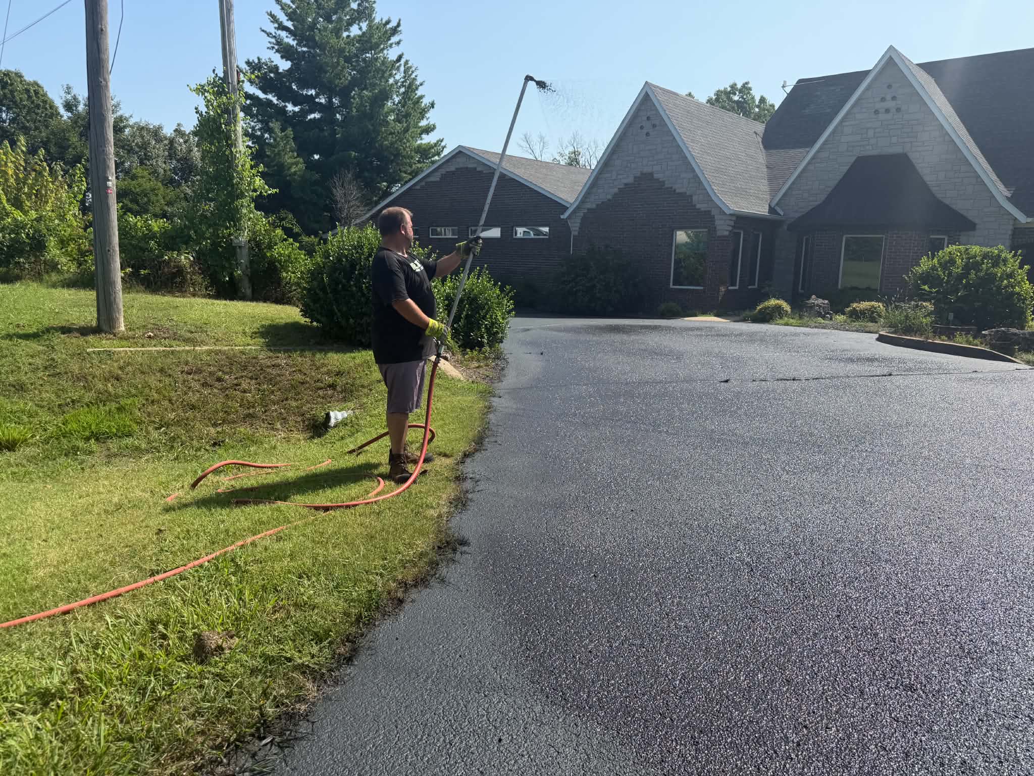 Professional Asphalt Maintenance Services in Wichita, KS NextGen technician applying sealcoat along a residential driveway edge