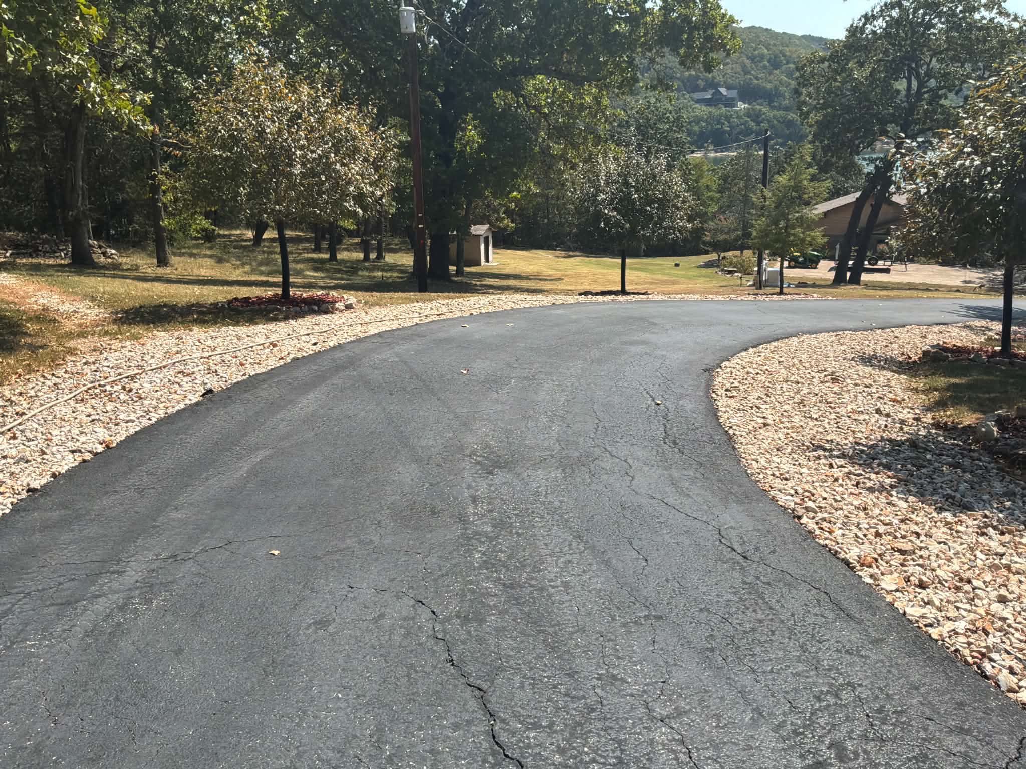 Weathered curved driveway bordered by stone landscaping in Lampe, Missouri