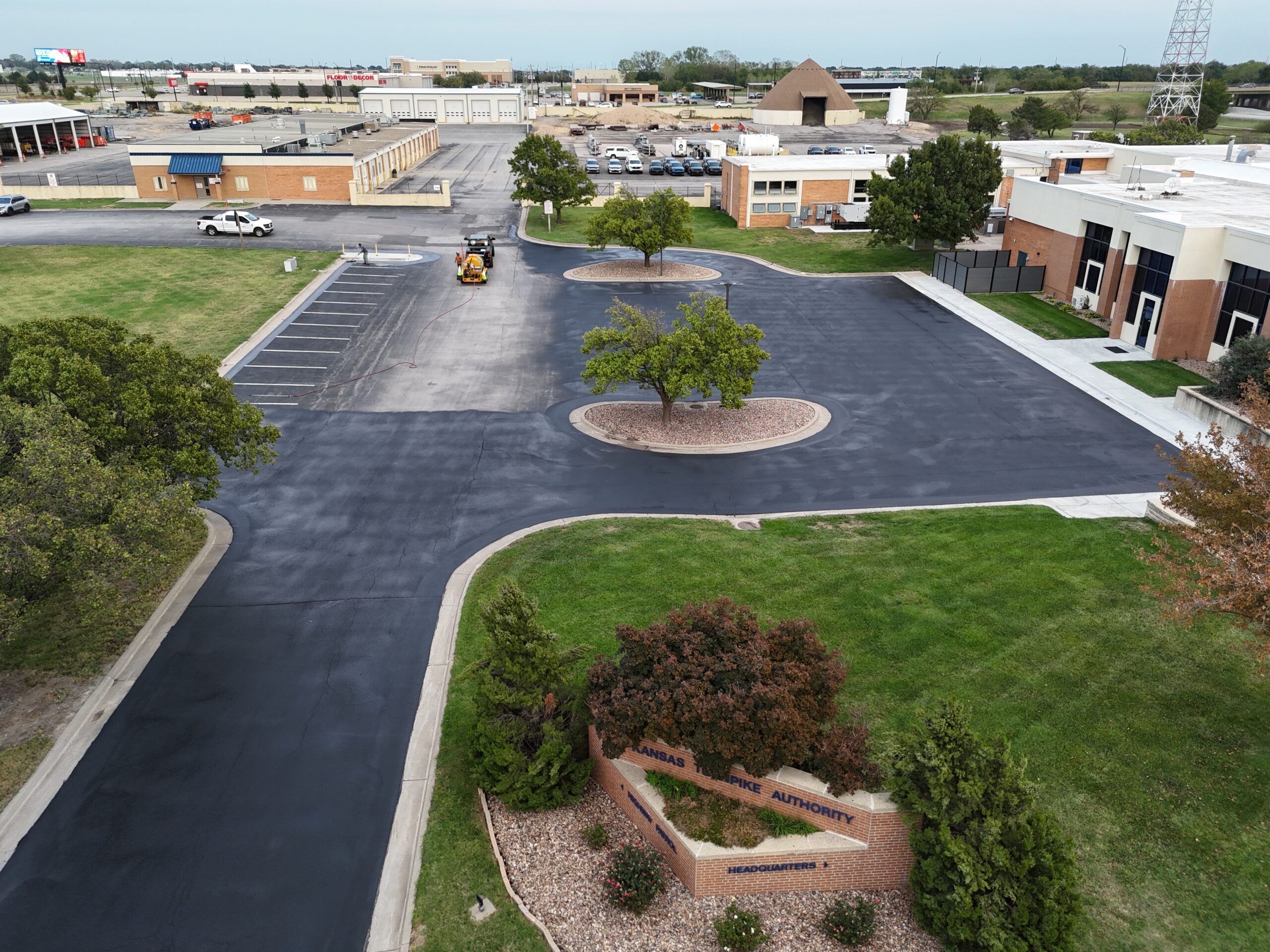 KTA Wichita Headquarters Sealcoating Aerial view of sealcoating work underway in the KTA Wichita headquarters parking area, with the brick entrance sign in the foreground