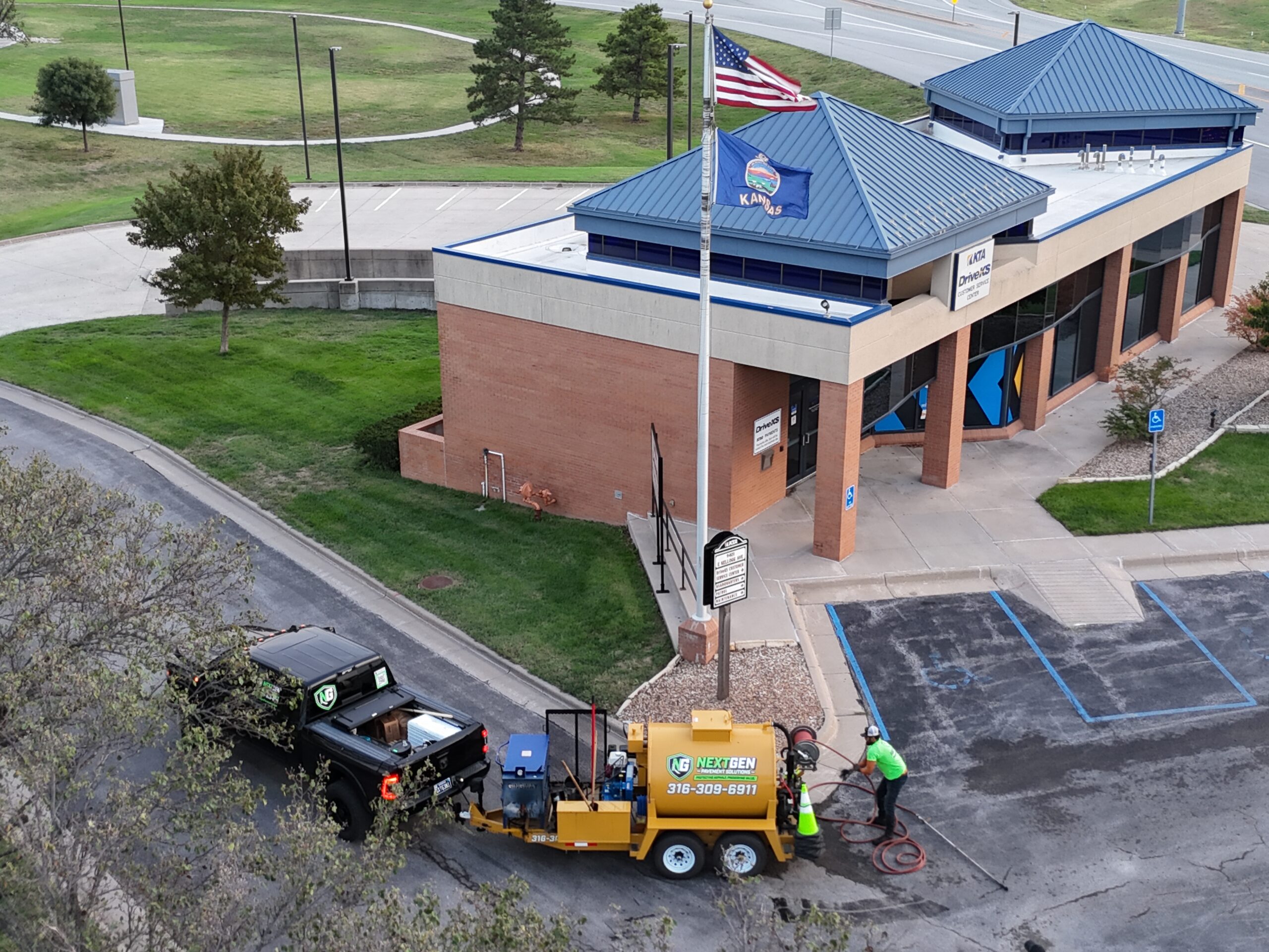 KTA Wichita Headquarters Sealcoating NextGen crew member and sealcoating trailer outside the KTA DriveKS Customer Service Center at the Wichita site