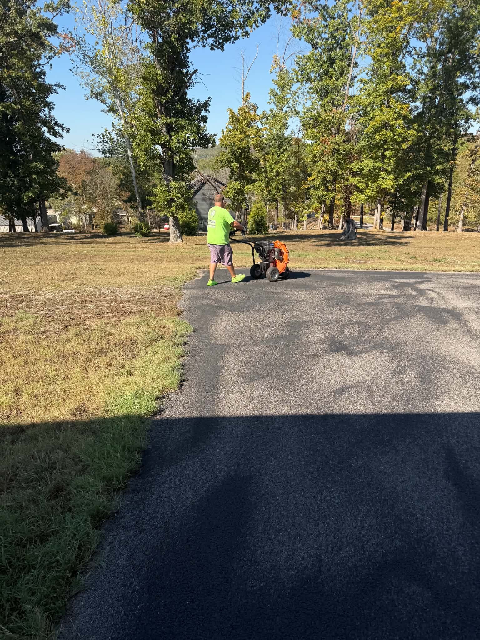 NextGen worker using a blower to prepare existing asphalt at a Cape Fair driveway.