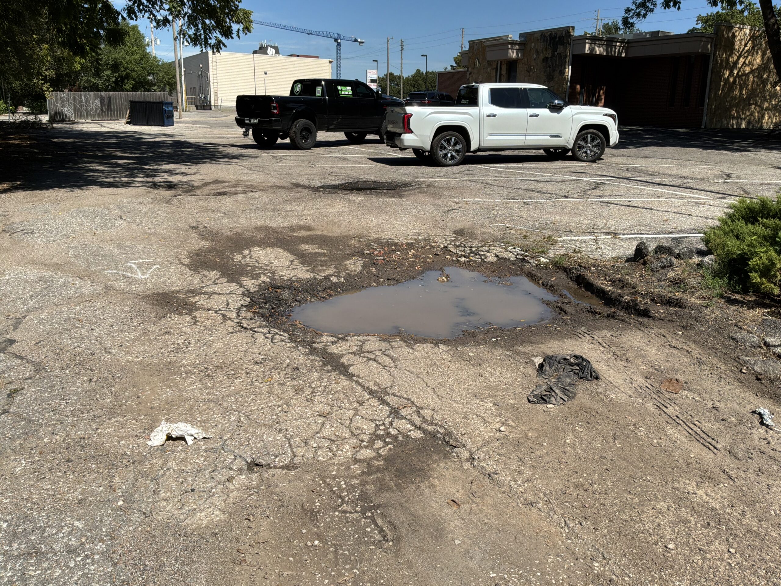 College Hill Pediatrics | Asphalt Repair & Sealcoating in Wichita Water-filled crater and broken asphalt at College Hill Pediatrics before repair